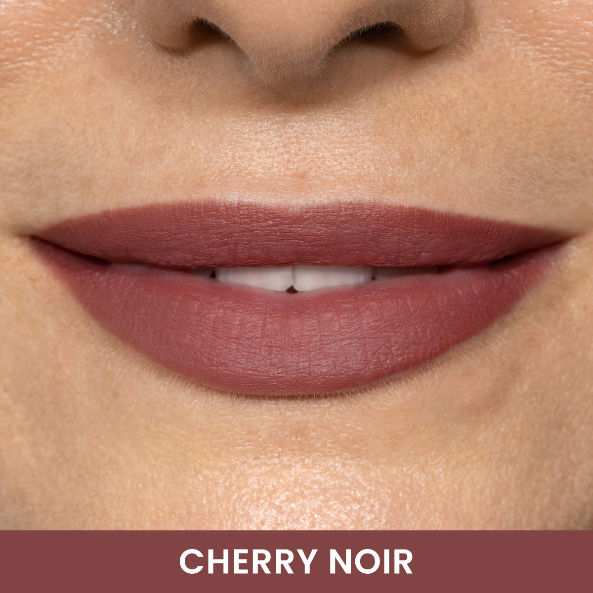 A close-up of a persons lips wearing matte cherry-colored lipstick. The skin tone is light, and the lipstick shade is labeled CHERRY NOIR at the bottom of the image.