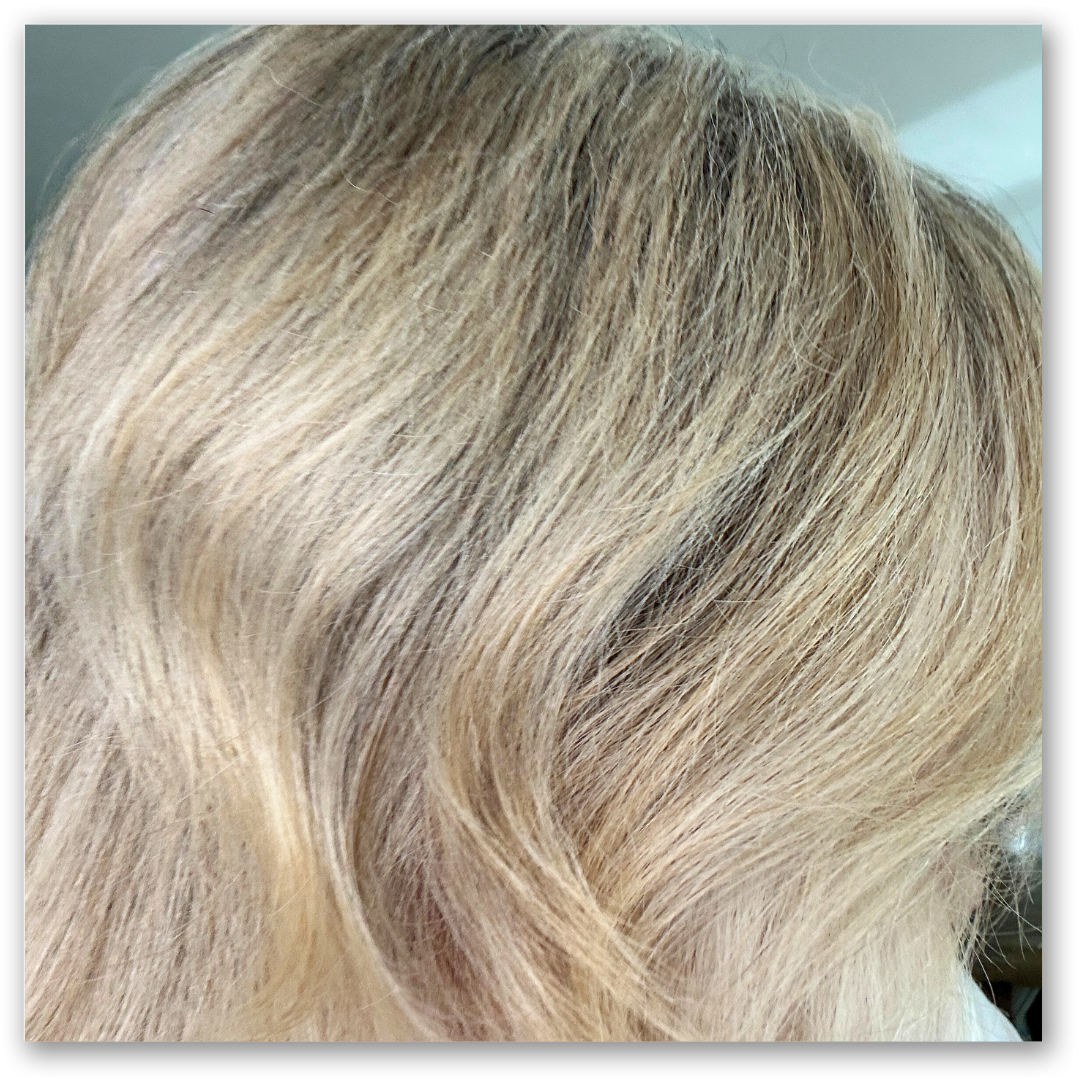 Close-up of wavy, light blonde hair with subtle shades of darker blonde and brown, showing soft texture and natural highlights.