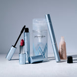 A selection of PrimePrometics™ Build Your Own Bundle beauty essentials—mascara, lipstick, cleanser, tube, and lip gloss—styled on a light surface with a minimalist gray background.