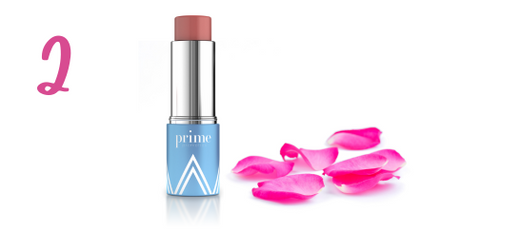 A pink makeup stick labeled prime stands upright next to scattered pink rose petals on a white background. The number 2 appears in pink on the left side.