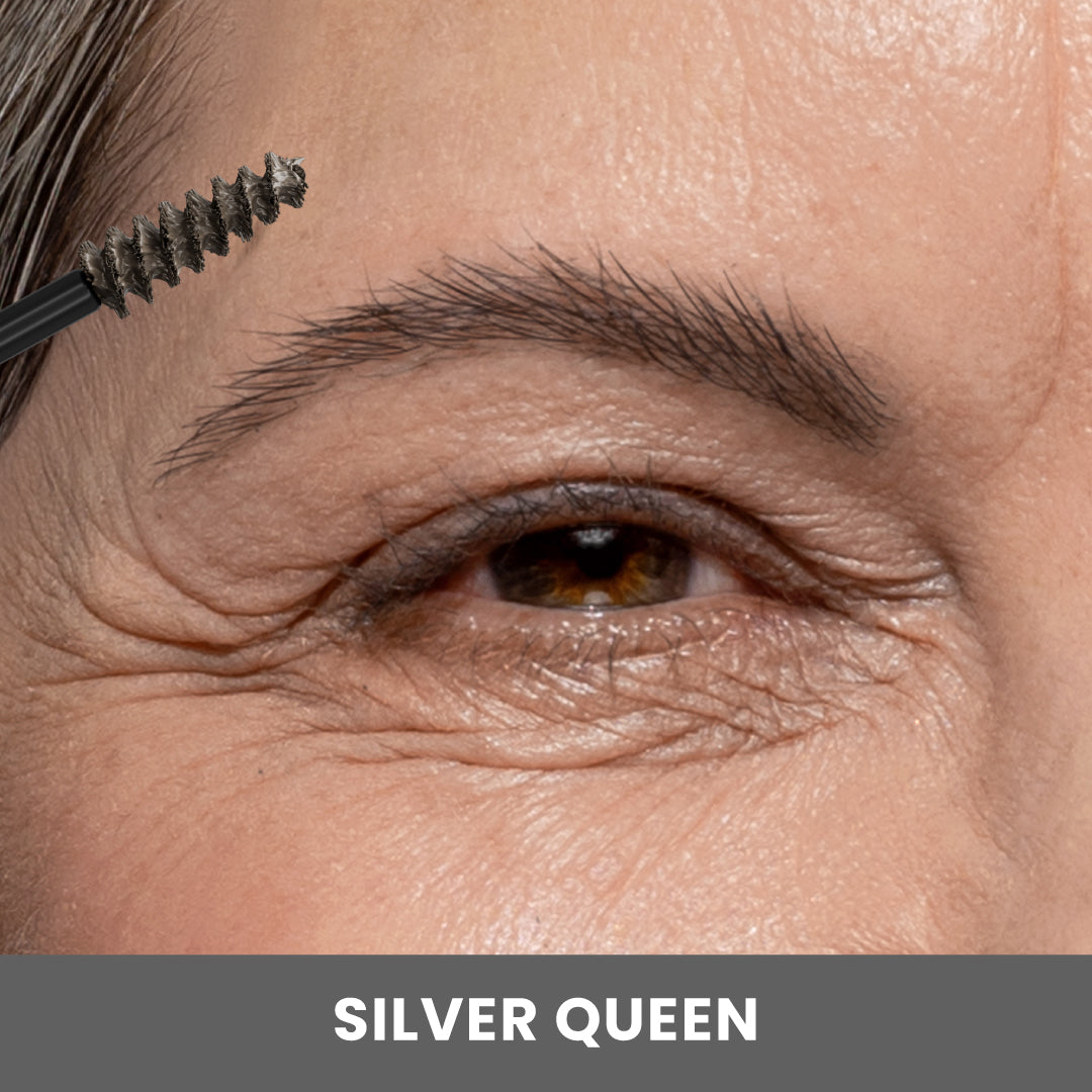 A close-up of an older persons eye and eyebrow as a mascara wand brushes the eyebrow hair. The image is labeled SILVER QUEEN at the bottom.