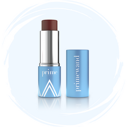 A blue tube of Prime Everyday balm with the cap off, revealing a dark brown stick inside. The cap, printed with the brand name, stands upright beside the product on a light blue circular background.