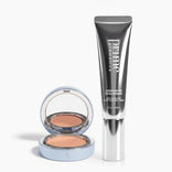 A compact with cream makeup and a mirror sits next to a metallic tube labeled “Bright Eyes & Blurred Lines Duo” by PrimePrometics™ on a white background.