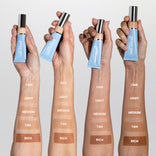 Three arms with different skin tones each display swatches labeled FAIR, LIGHT, MEDIUM, TAN, and RICH, holding blue tubes of Primaskin foundation in front of a light background.