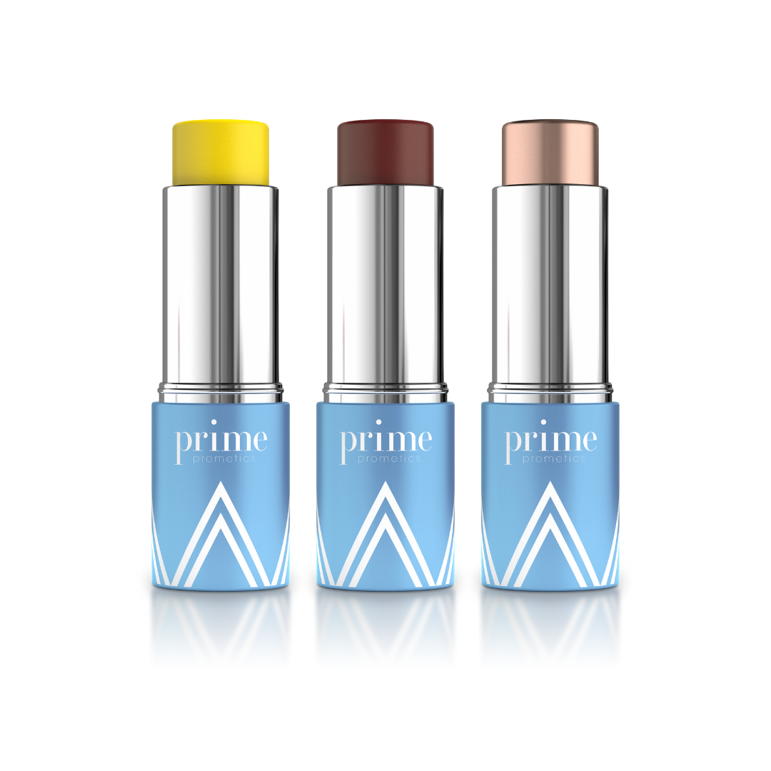 Three tubes of makeup sticks with silver tops and blue bases labeled prime are shown. The sticks display yellow, brown, and peach shades, standing upright on a white background.