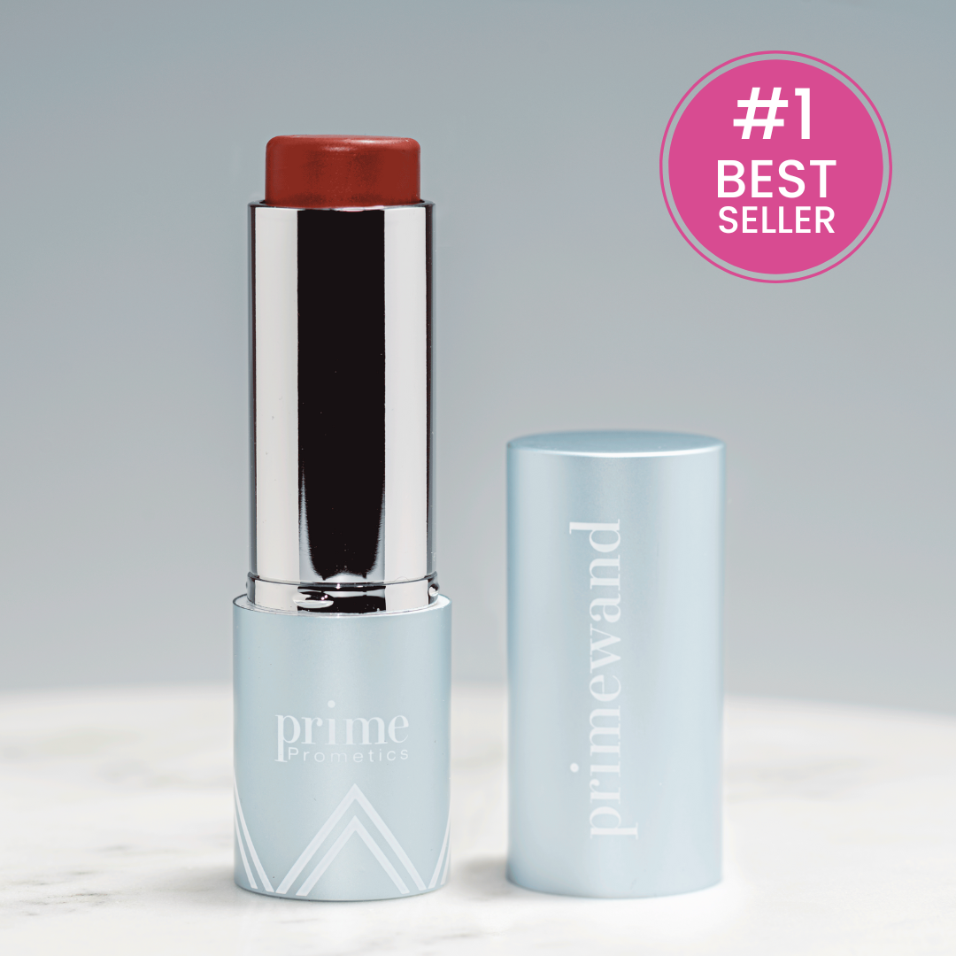 A silver and light blue tube of Prime Prometics PrimeWand lipstick stands open on a white surface, with its cap beside it. A pink #1 Best Seller badge is shown in the upper right corner.