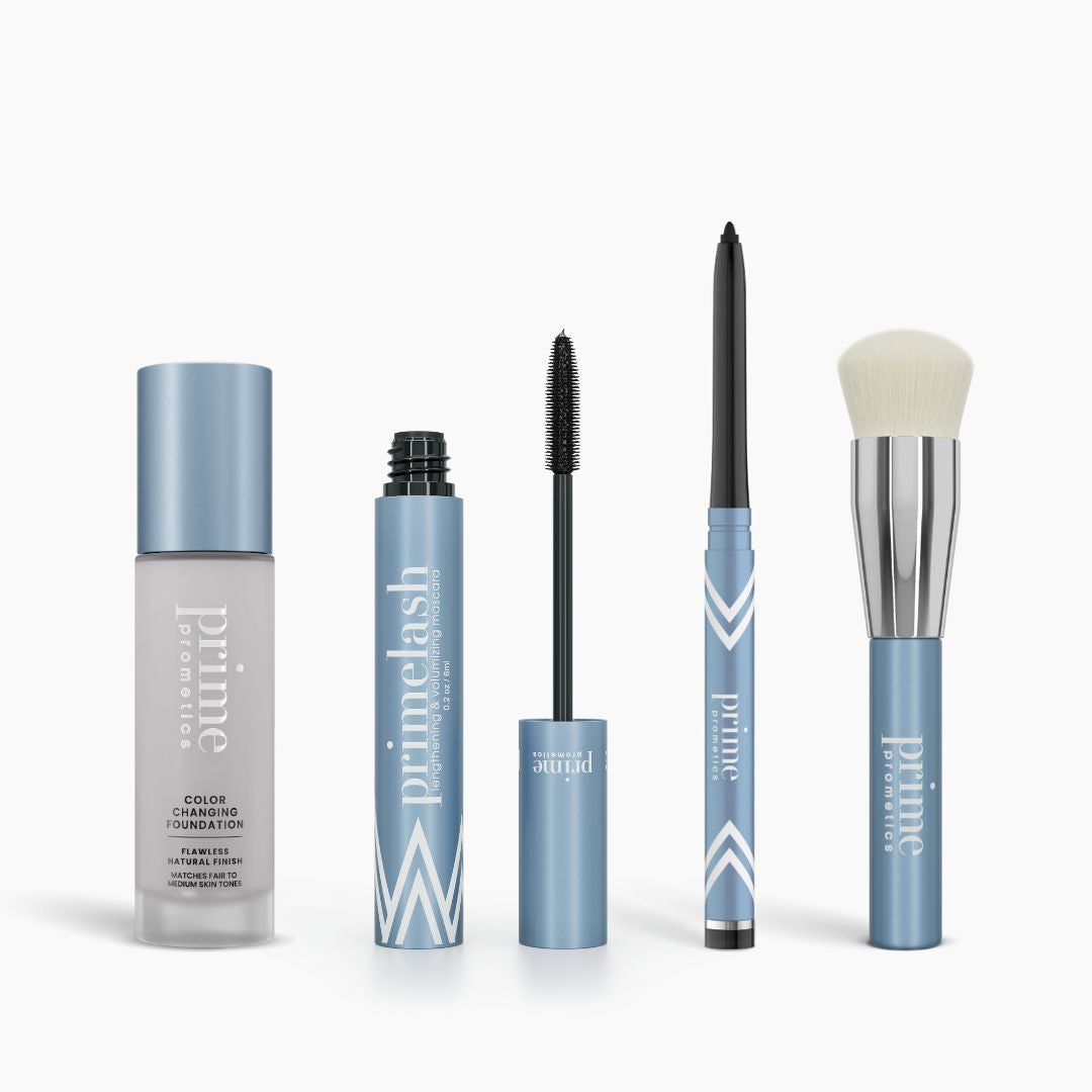The PrimePrometics™ Prime Perfection Bundle features Color Changing Foundation, PrimeLash Mascara, PrimeEyes Glide Eyeliner, and a makeup brush in light blue and silver packaging displayed on a white background.