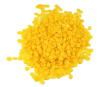 A pile of small, bright yellow wax beads on a white background.