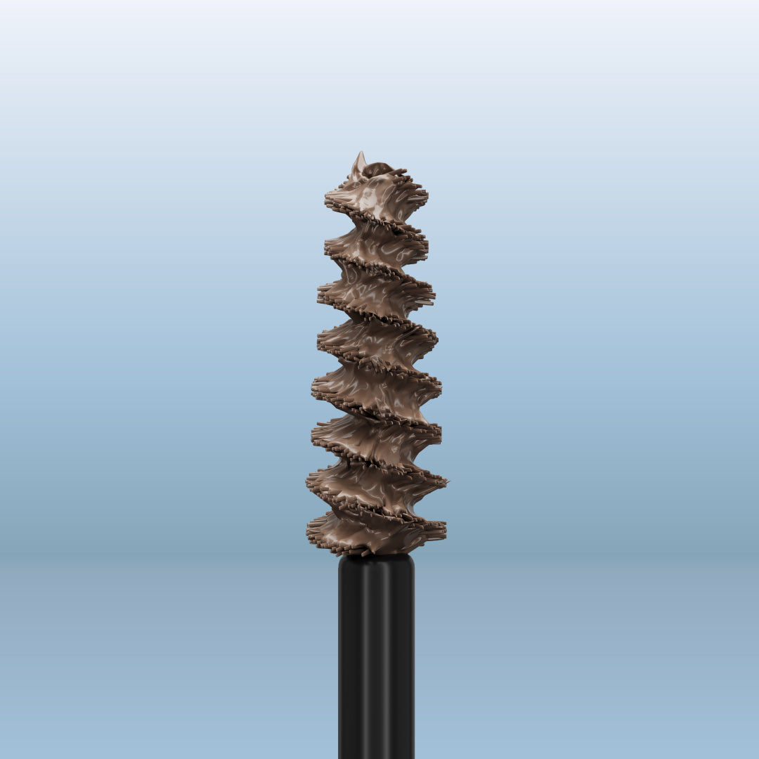 A close-up of a mascara or eyebrow spoolie wand with brown makeup product on its bristles, set against a gradient light blue background.