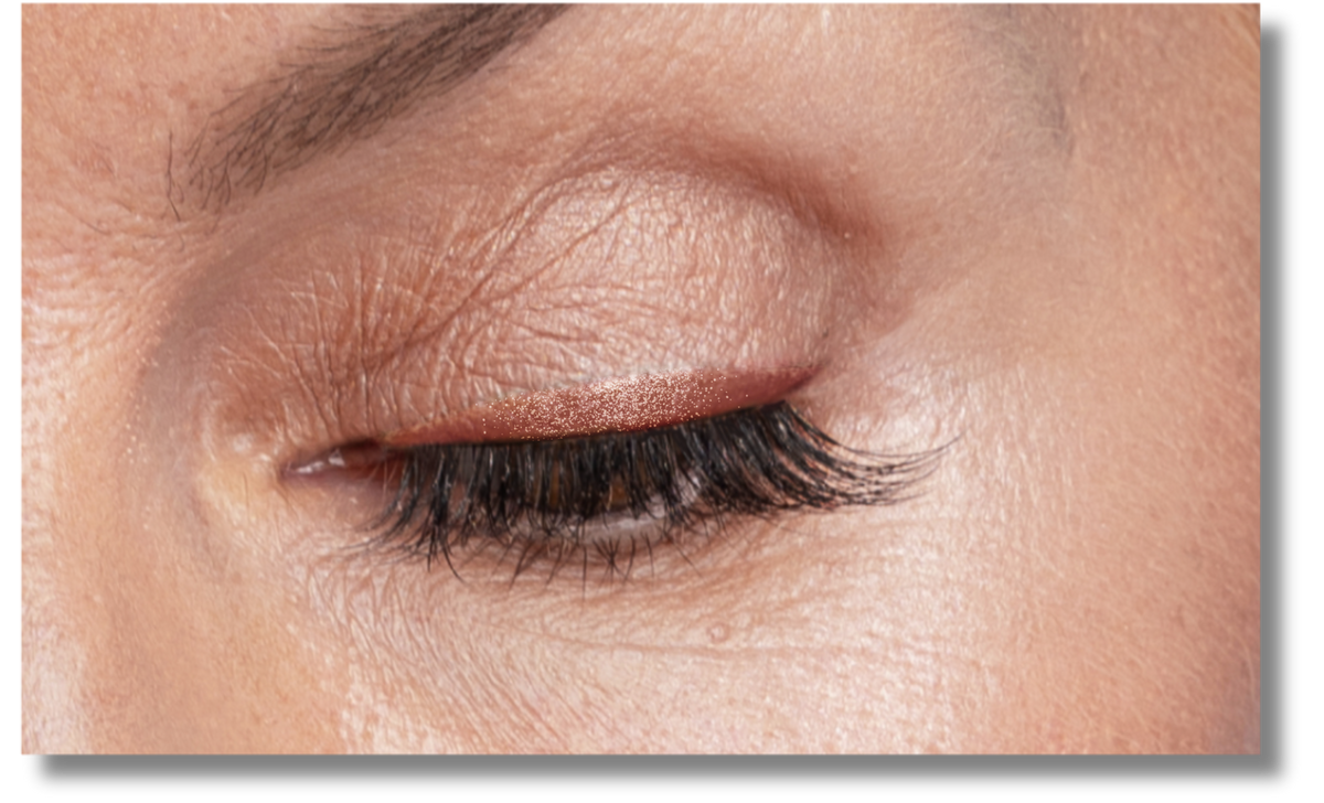 A close-up of a closed eye with long, dark eyelashes and well-groomed eyebrow. The skin shows natural texture and fine lines.