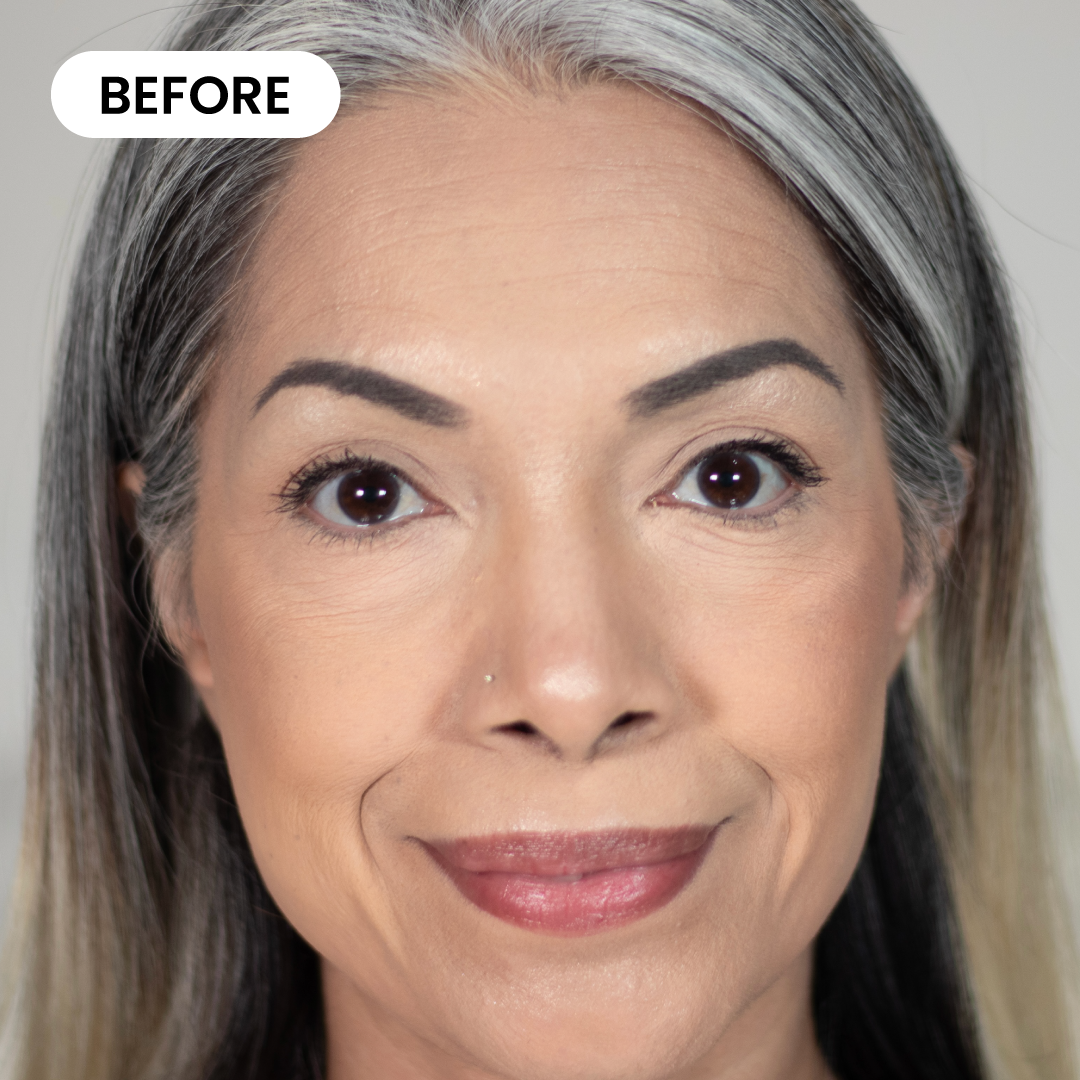 Close-up of a middle-aged woman with smooth skin, gray and black hair, subtle makeup, and a slight smile. The word BEFORE appears in a white rounded rectangle in the upper left corner.