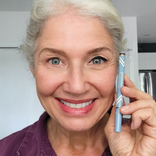Mature woman with white hair holding the Prime Prometics PrimeEyes Liquid Eyeliner pen near her face, eyeliner applied
