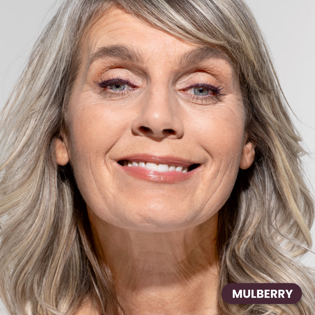 Mature woman with gray hair wearing Prime Prometics PrimeEyes Glide Eyeliner in Mulberry, a deep berry shade