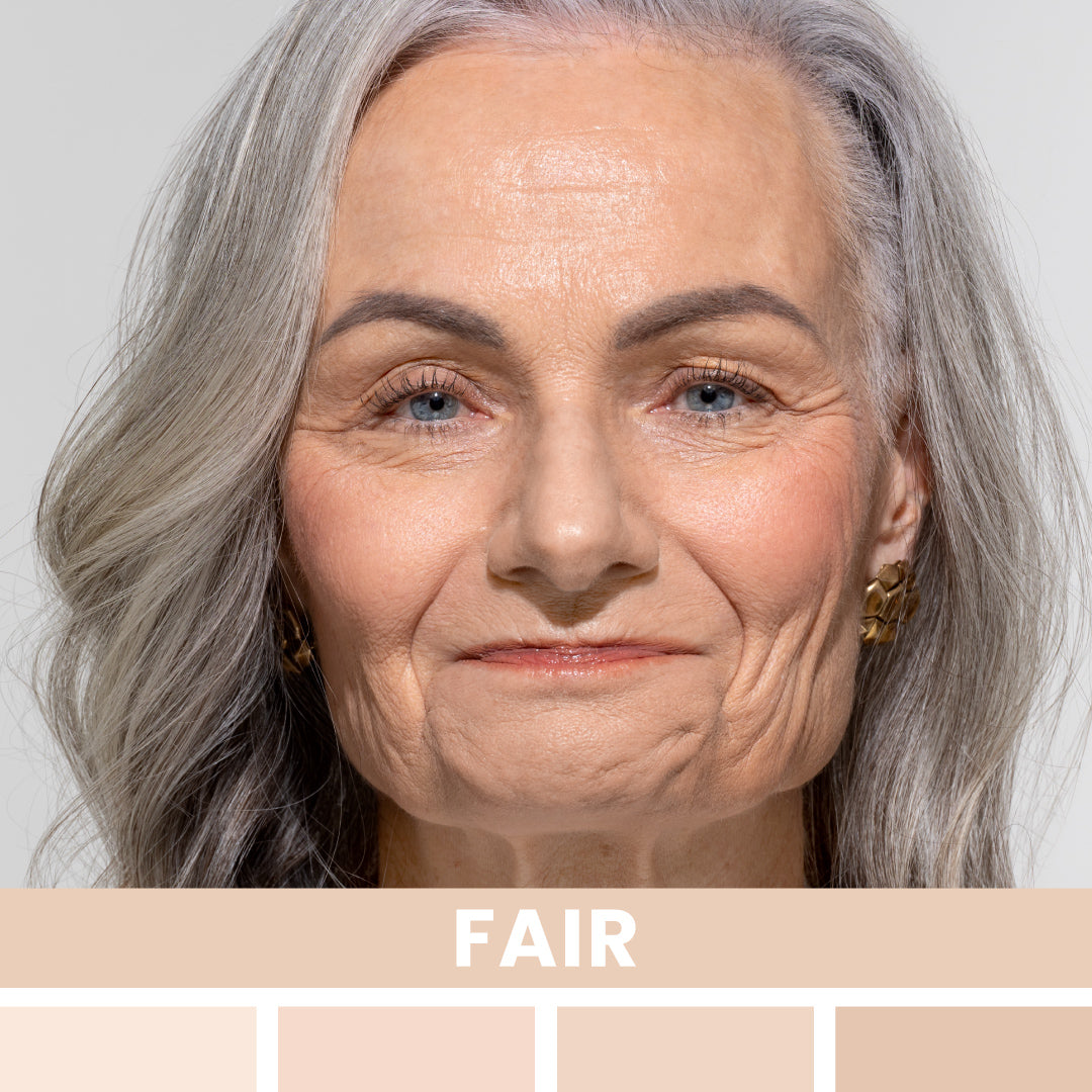 Close-up of an older woman with long, gray hair, blue eyes, and fair skin, smiling slightly. The word FAIR appears below, with different fair skin tone swatches underneath.
