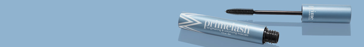 A light blue tube of PrimeLash mascara with the wand applicator partially removed, lying on a matching blue background.