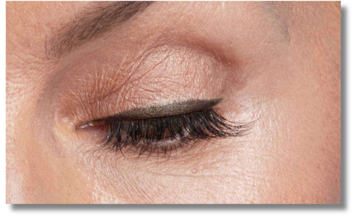 A close-up of a closed eye with winged black eyeliner and long, thick eyelashes. The skin around the eye shows fine lines and natural texture.