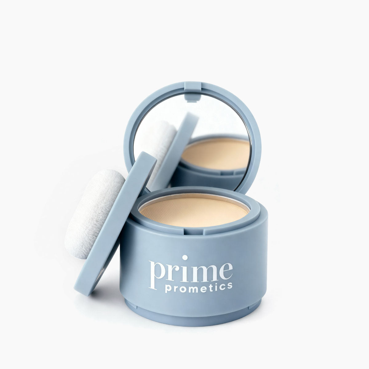 An open, round light blue compact labeled PrimePrometics™ Instant Coverage Hairline Powder reveals a mirror, beige powder for gray root coverage, and a white applicator puff on the side against a white background.
