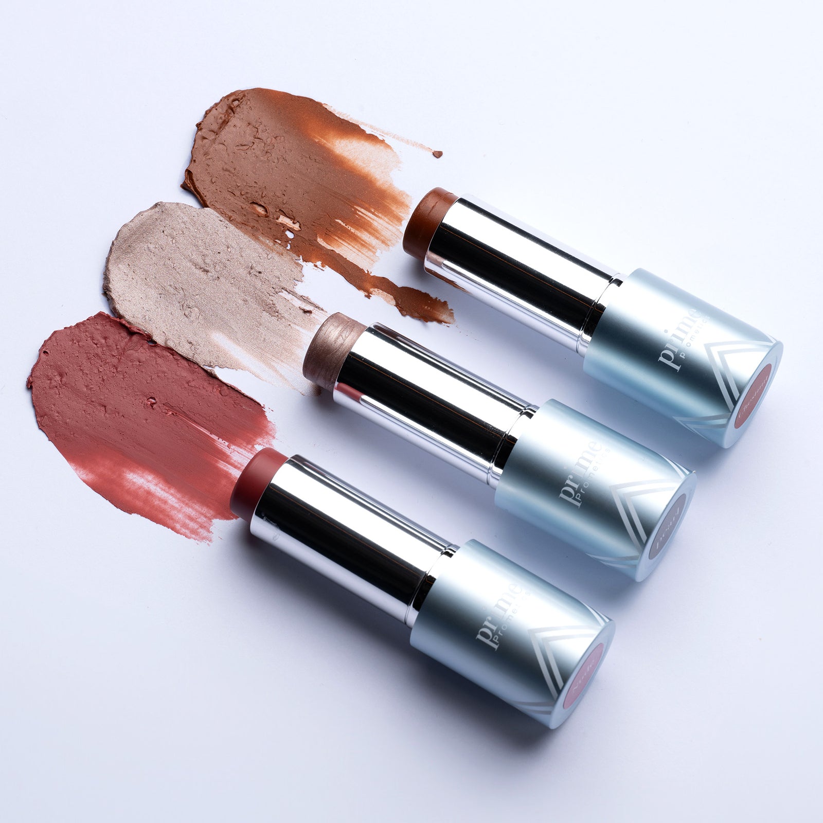 Three makeup sticks from the PrimeWand Contour Kit by PrimePrometics™—including bronzer, highlighter, and blush—stand upright in blue and silver tubes against a white background.