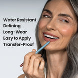 A smiling woman with long gray hair applies PrimePrometics™ Velvet Lip Contour, a lip liner for mature lips. Text beside her reads: “Water Resistant, Defining, Long-Wear, Easy to Apply, Transfer-Proof.”.