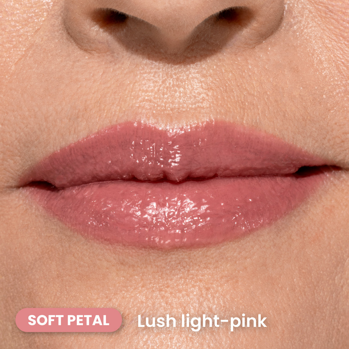 Close-up of lips wearing glossy, lush light-pink lipstick. The skin around the lips is smooth, and the color is labeled Soft Petal in the lower left corner. Text also reads Lush light-pink.
