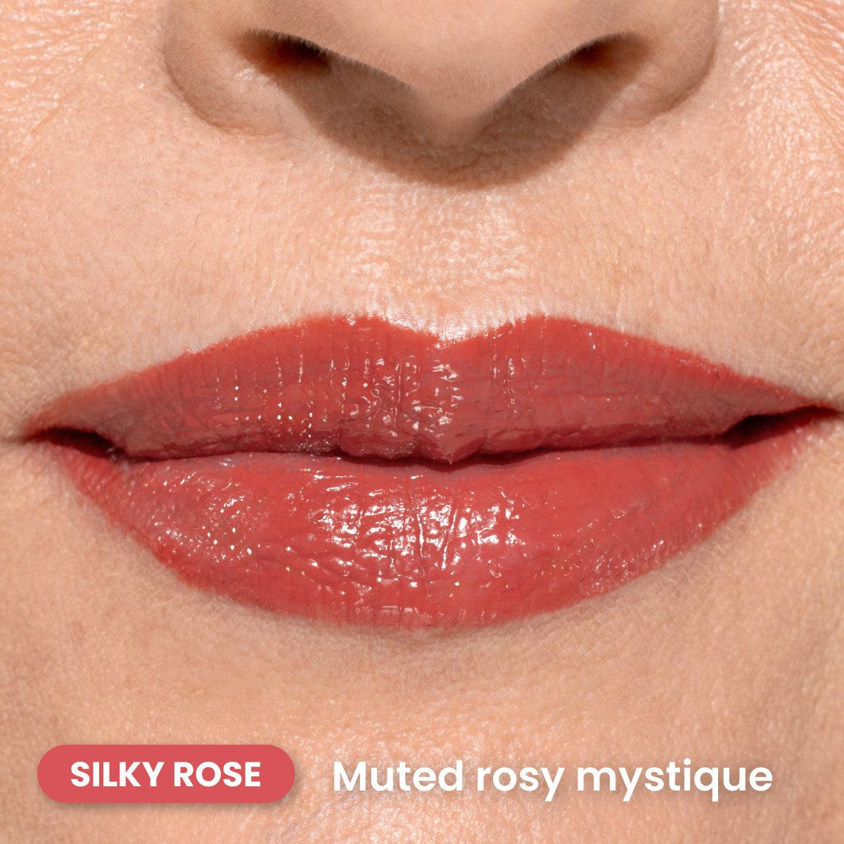 Close-up of a persons lips wearing glossy, muted rose-colored lipstick. The skin is light with visible texture. Text reads SILKY ROSE and Muted rosy mystique in the bottom left corner.