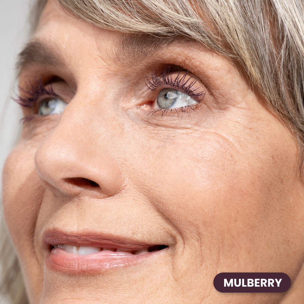 Mature woman with gray hair wearing Prime Prometics PrimeLash Mascara in Mulberry, a deep berry shade