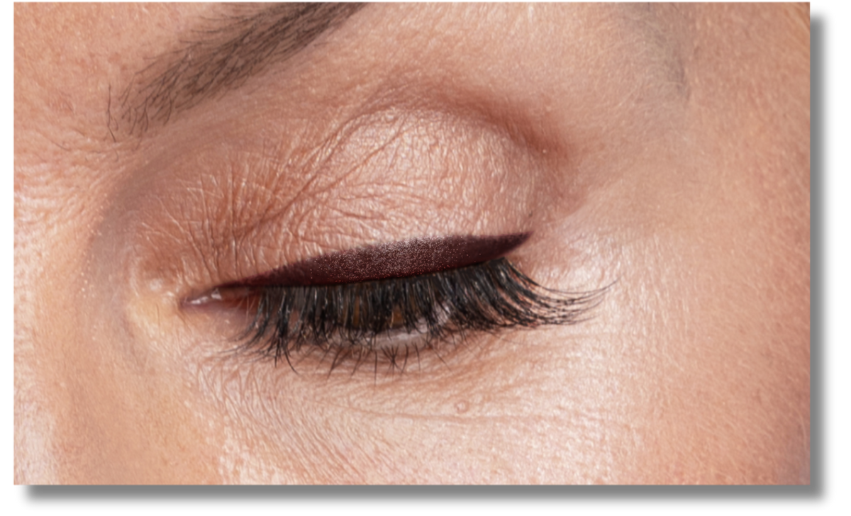 A close-up of a closed eye with smooth skin, showing neatly groomed eyebrow, dark eyeliner, and long, curled eyelashes.