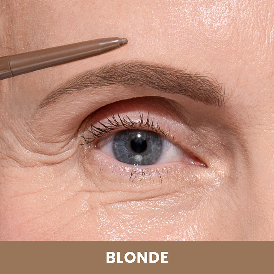 A close-up of a blue eye with defined eyebrow, as a brown eyebrow pencil is applied. The background below features the word BLONDE in white text on a tan-colored strip.