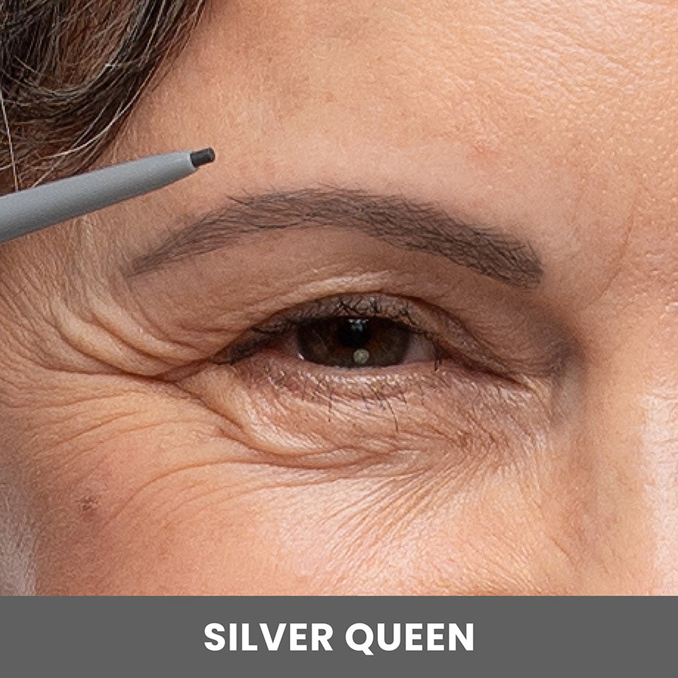 A close-up of a womans eye and eyebrow as she fills in her eyebrow with a gray pencil. The bottom of the image has a gray bar with the text SILVER QUEEN.