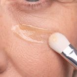 A PrimeLift Precision Applicator Brush applies PrimeLift Instant Eye Tightener serum to the skin under an eye.