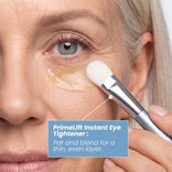 A person uses a PrimeLift Precision Applicator Brush to pat and blend a thin, even layer of eye tightener under their eye.