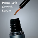 A close-up of an open PrimePrometics™ Both Mascaras + Serum bottle with the applicator brush above it, highlighting the lash serum. The product name is displayed on the left in white text against a gray background.