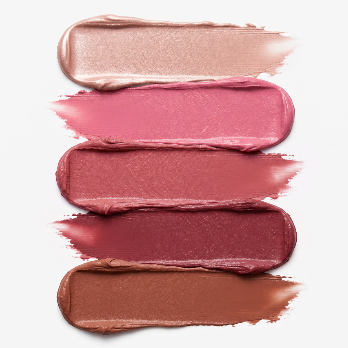 Five horizontal swipes of creamy PrimePrometics™ PrimeWands 5-in-1 Makeup Wand are shown in gradient nude, pink, mauve, and brown shades against a white background. The skincare-infused formula glides on smoothly for buildable, customizable coverage.