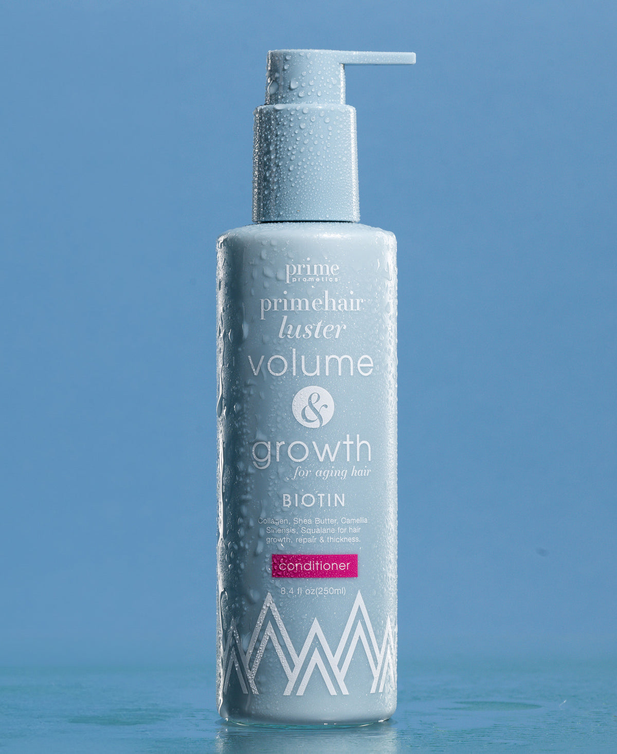 A light blue bottle of Prime Hair Luster Volume & Growth Conditioner with a pump top, covered in water droplets, is set against a blue background. The label highlights biotin as a key ingredient.