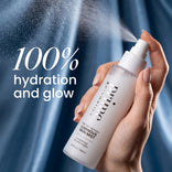 A hand holds a Prep-Set-Refresh Luminous Skin Mist, emitting a fine spray of luminous mist with a text overlay reading 100% hydration and glow.