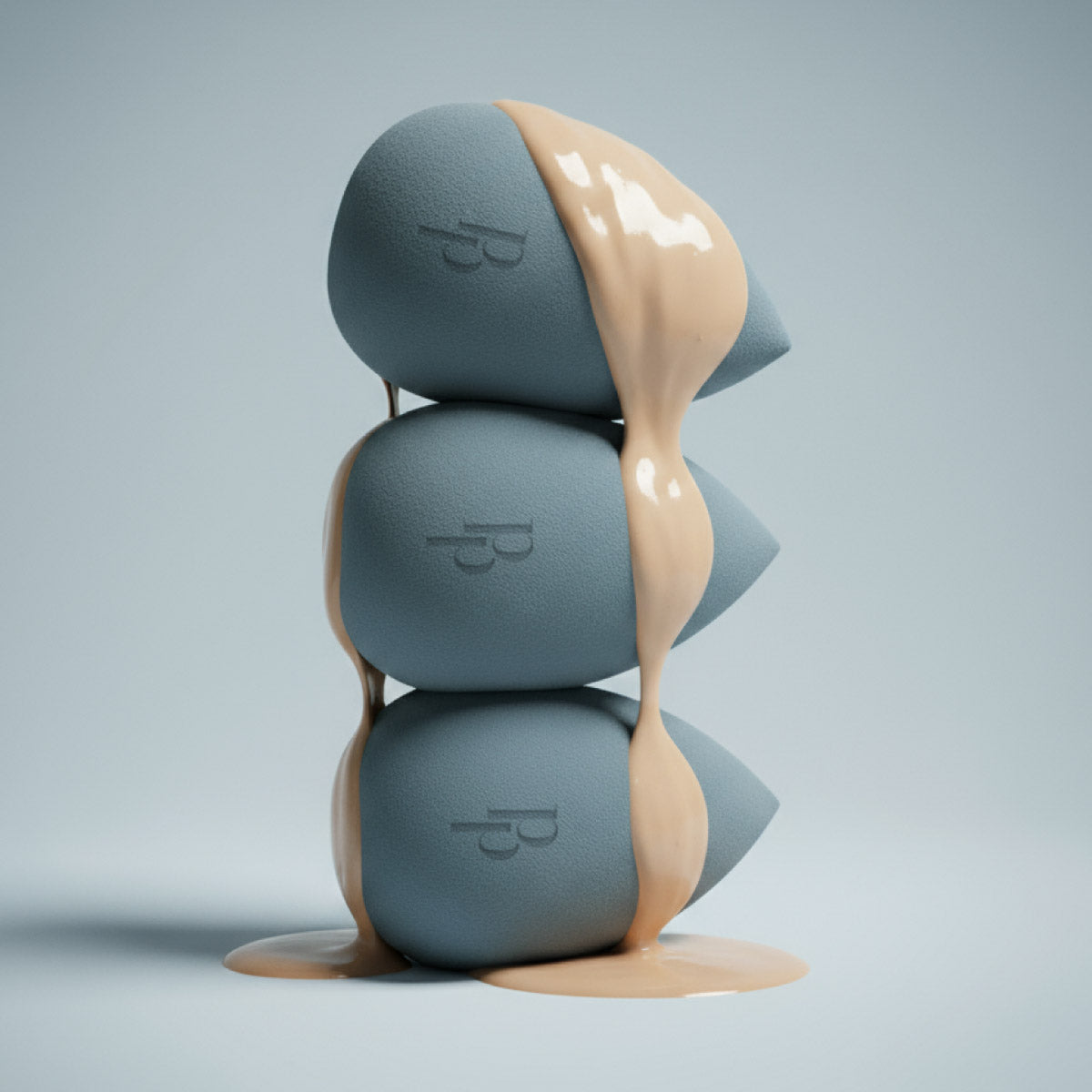 Three gray makeup sponges stacked vertically with liquid foundation dripping over them and pooling at the bottom, against a light gray background.