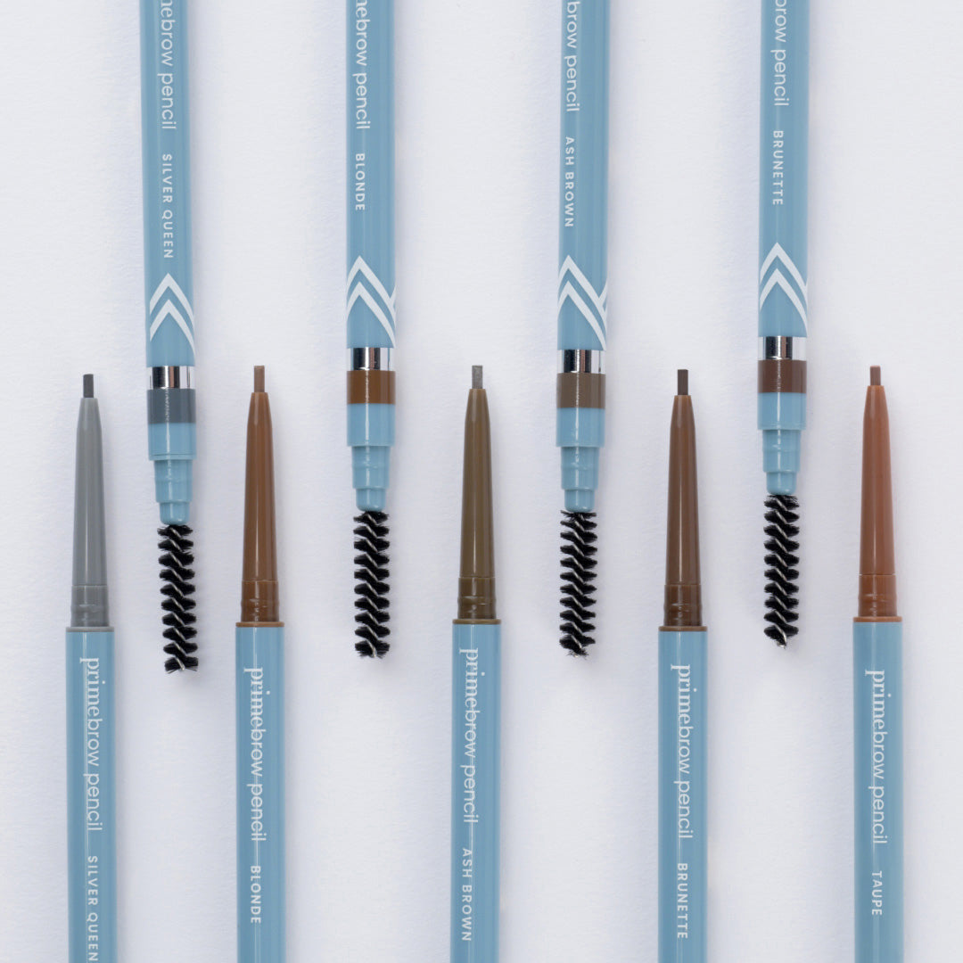 Five blue eyebrow pencils with spoolie brushes are arranged vertically. Each pencil is labeled with a different shade: Silver Queen, Blonde, Ash Brown, Brunette, and Taupe. Tips and brushes are visible.