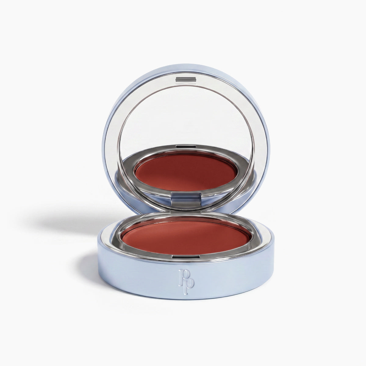 The PrimePrometics™ Undereye Brightening Corrector—a silver compact with mirror—holds a deep reddish-brown balm, perfect for blush, lip color, or as an undereye brightener. Displayed on a white background.
