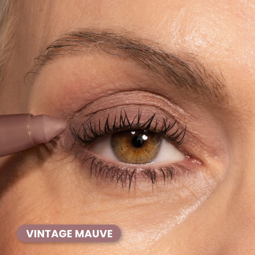A close-up of a person’s eye with mauve-colored eyeshadow and eyeliner. A mauve eye pencil is applied to the upper lash line. The text “VINTAGE MAUVE” appears at the bottom left.