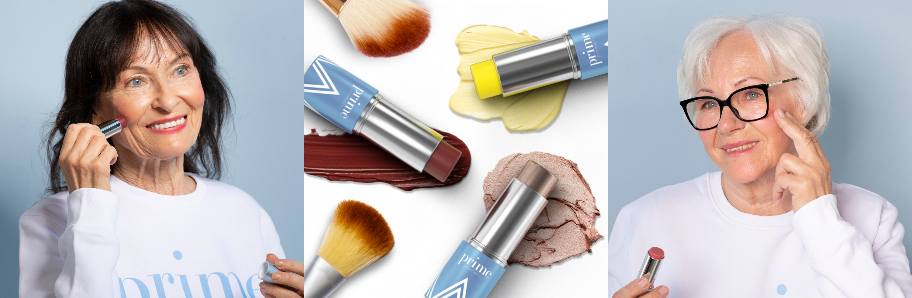 Two older women with light skin apply makeup, smiling, wearing white shirts. In the center, three blue makeup sticks and brushes rest on smears of lip, cheek, and foundation colors against a light background.
