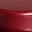 Close-up of a reddish-brown, slightly curved surface with some faint, small markings or scratches visible near the center. The texture appears smooth and slightly reflective.