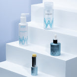 Four PrimePrometics™ Build Your Own Bundle skincare essentials are displayed on white stepped platforms—a pump bottle, spray, dropper, and stick balm—all in light blue and white packaging for pro-age beauty.